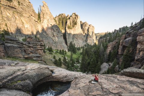 Hiker enjoying the view at Paradise Falls, where water carves through ancient rock formations amid lush valleys, one of the top hikes in Wyoming.
