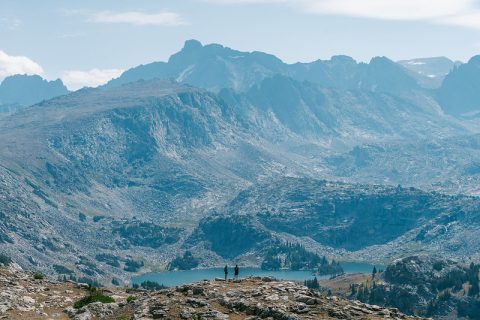 Hikers stand admiring a vast mountainous landscape of Cloud Peak Wilderness, a top thing to do for breathtaking views and exploration in Sheridan, Wyoming.