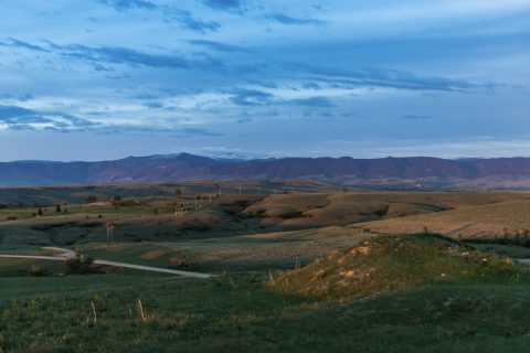 Dusk settles over Soldier Ridge, showcasing undulating hills and distant mountain views, a serene spot on the hiking trails in Sheridan.