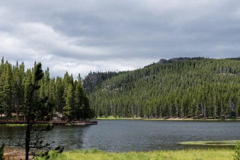 Peaceful Sibley Lake surrounded by dense pines and rocky hills, a picturesque destination for outdoor hiking near Sheridan, WY.