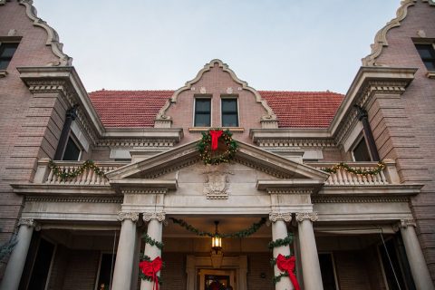 An historical building in Sheridan, WY adorned with traditional Christmas decorations, including wreaths and garlands, welcomes the festive things to do the season.