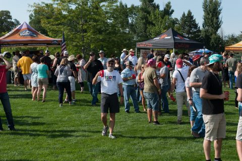 Crowd of visitors enjoying the sunny day at Sheridan Brewfest, with various brewery tents in the background.