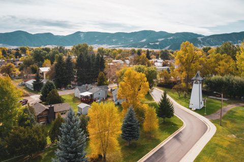 Aerial view of Dayton, Wyoming, showcasing amazing fall colors, winding roads, and a distinctive white bell tower, set against a backdrop of mountain scenery.