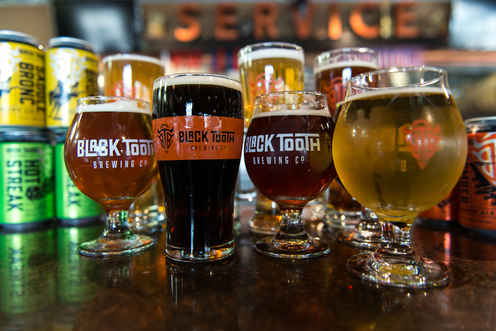 An assortment of craft beers from Black Tooth Brewing Co., with a variety of ales and stouts in branded glasses, showcasing the brewery's selection.