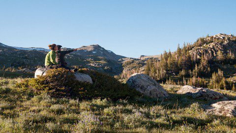 A hiker sitting on a boulder and gazing at the Bighorn Mountains in Wyoming.